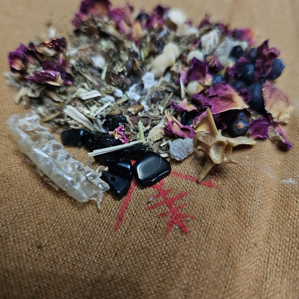 Herbal mix with black stones and crystals on a textured brown surface