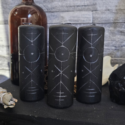 Set of black bottles with engraved symbols on a wooden surface